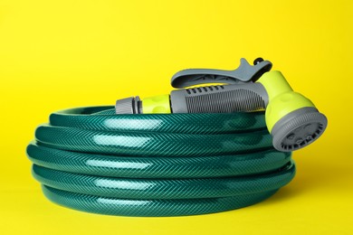 Photo of Watering hose with sprinkler on yellow background