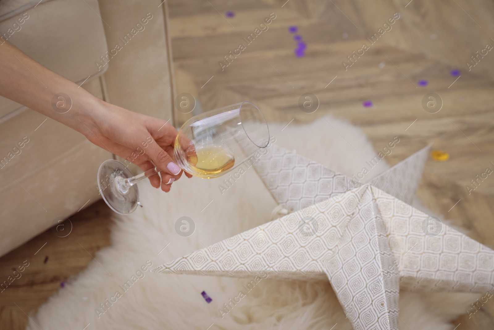 Photo of Woman with glass of wine in messy room after New Year party, closeup