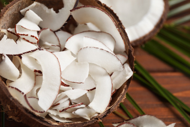 Photo of Tasty coconut chips in shell on table, closeup