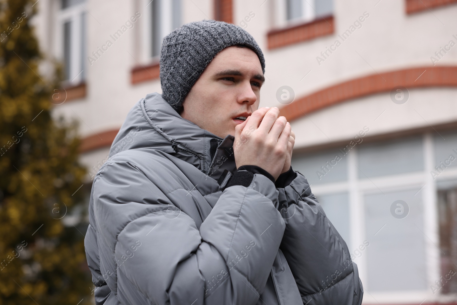 Photo of Sick young man coughing on city street. Cold symptoms