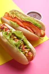 Photo of Delicious hot dogs with lettuce on color background, closeup