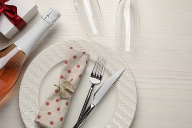 Photo of Beautiful table setting with gift box and bottle of sparkling wine for romantic dinner, flat lay