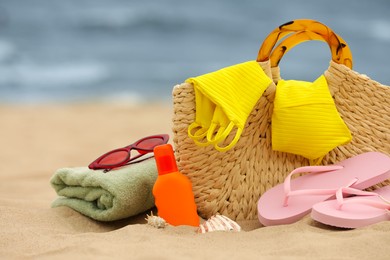 Photo of Bag and different beach objects on sand near sea