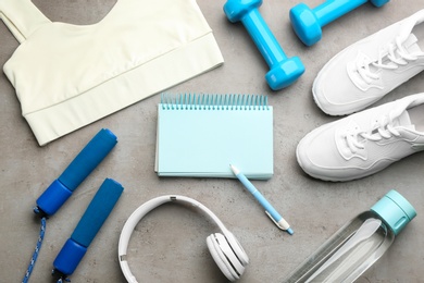 Photo of Flat lay composition with sportswear, notebook and equipment on grey background. Gym workout plan