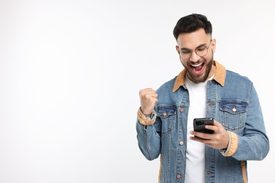 Happy young man using smartphone on white background, space for text