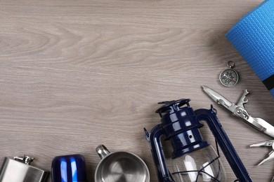 Photo of Flat lay composition with different camping equipment on wooden background, space for text