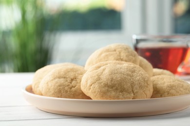 Delicious sugar cookies and cup of tea on white wooden table, closeup