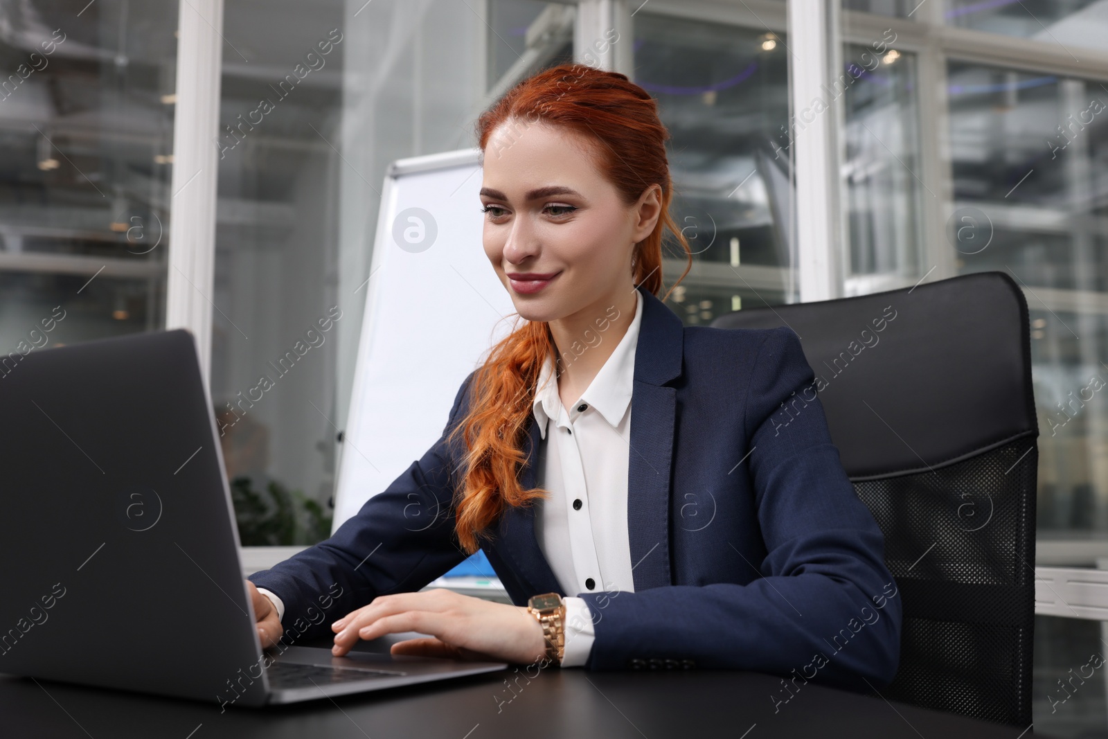 Photo of Happy woman working with laptop at black desk in office