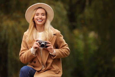 Autumn vibes. Portrait of happy woman with camera outdoors, space for text