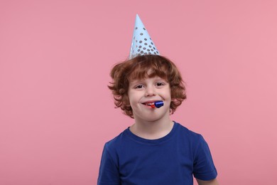 Photo of Happy little boy in party hat with blower on pink background