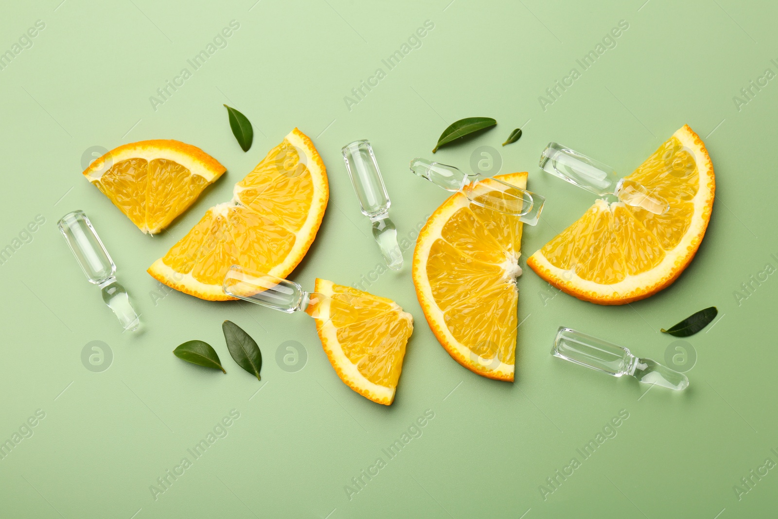 Photo of Skincare ampoules with vitamin C, slices of orange and leaves on light green background, flat lay