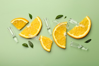 Photo of Skincare ampoules with vitamin C, slices of orange and leaves on light green background, flat lay