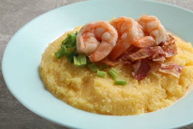 Plate with fresh tasty shrimps, bacon, grits and green onion on grey table, closeup