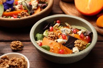 Photo of Delicious persimmon salad with cheese and pomegranate served on wooden table