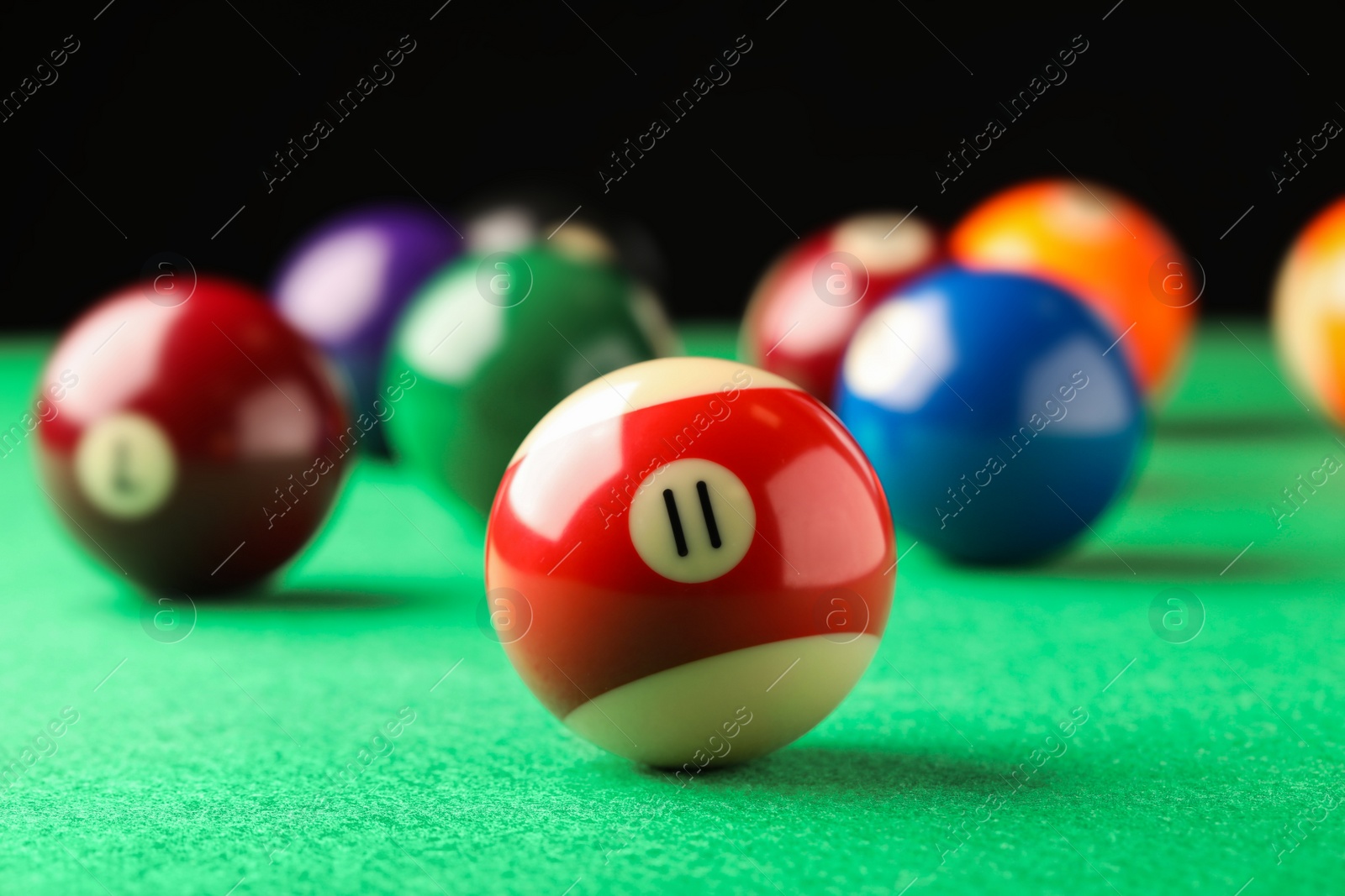 Photo of Billiard ball with number 11 on green table, closeup