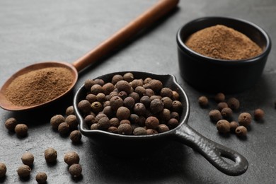 Ground and whole allspice berries (Jamaica pepper) on black table, closeup