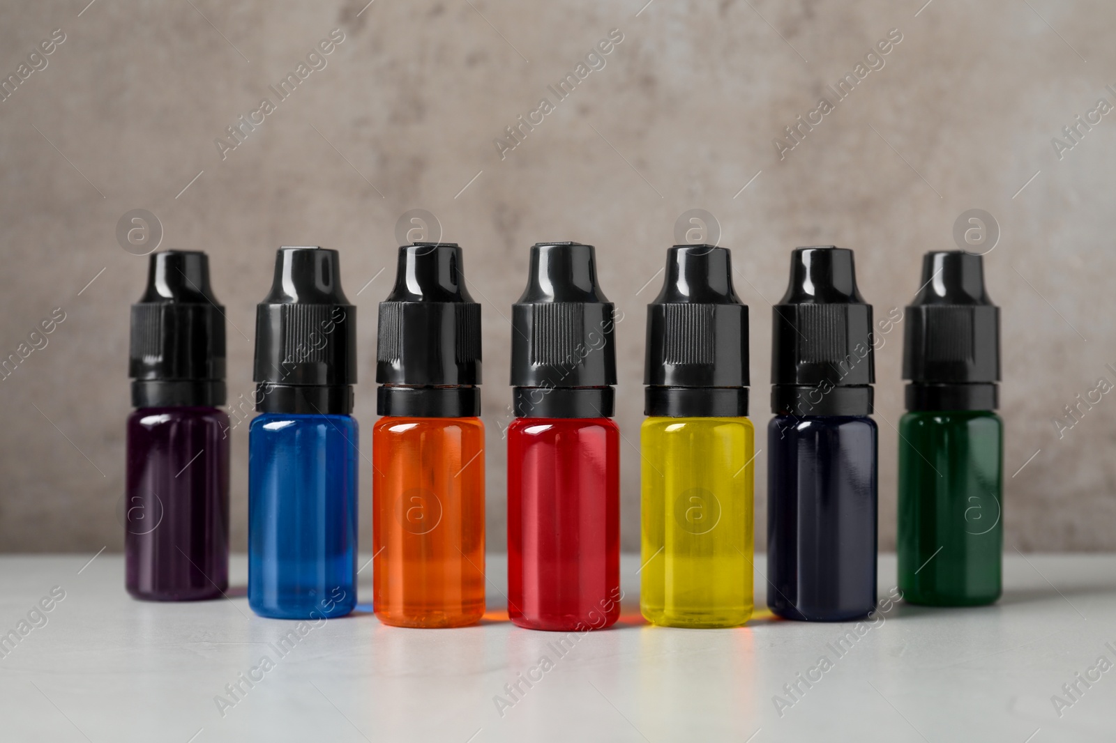 Photo of Bottles with different food coloring on white table