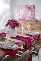 Pink peonies on table with beautiful setting and rattan chairs in dining room