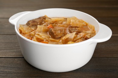 Photo of Tasty cabbage soup with meat and carrot on wooden table, closeup