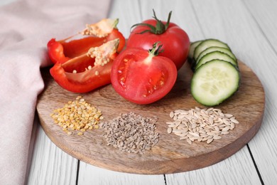 Photo of Fresh cucumbers, red bell peppers, tomatoes and vegetable seeds on white wooden table, closeup