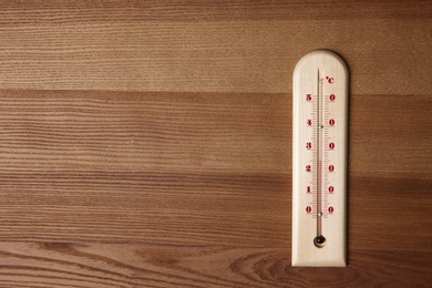 Photo of Weather thermometer on wooden table, top view. Space for text