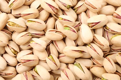 Tasty unpeeled pistachios as background, top view