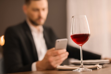 Photo of Glass of delicious wine and blurred man on background