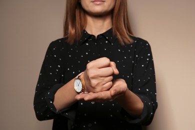 Photo of Woman showing word CRUCIFY in sign language on color background, closeup