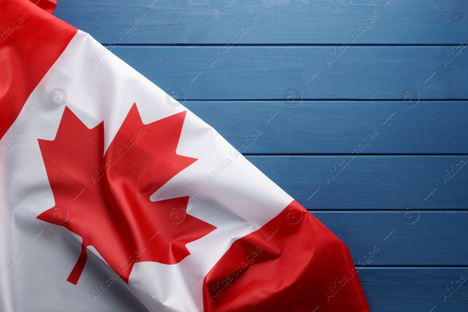 Photo of Flag of Canada on blue wooden table, top view. Space for text