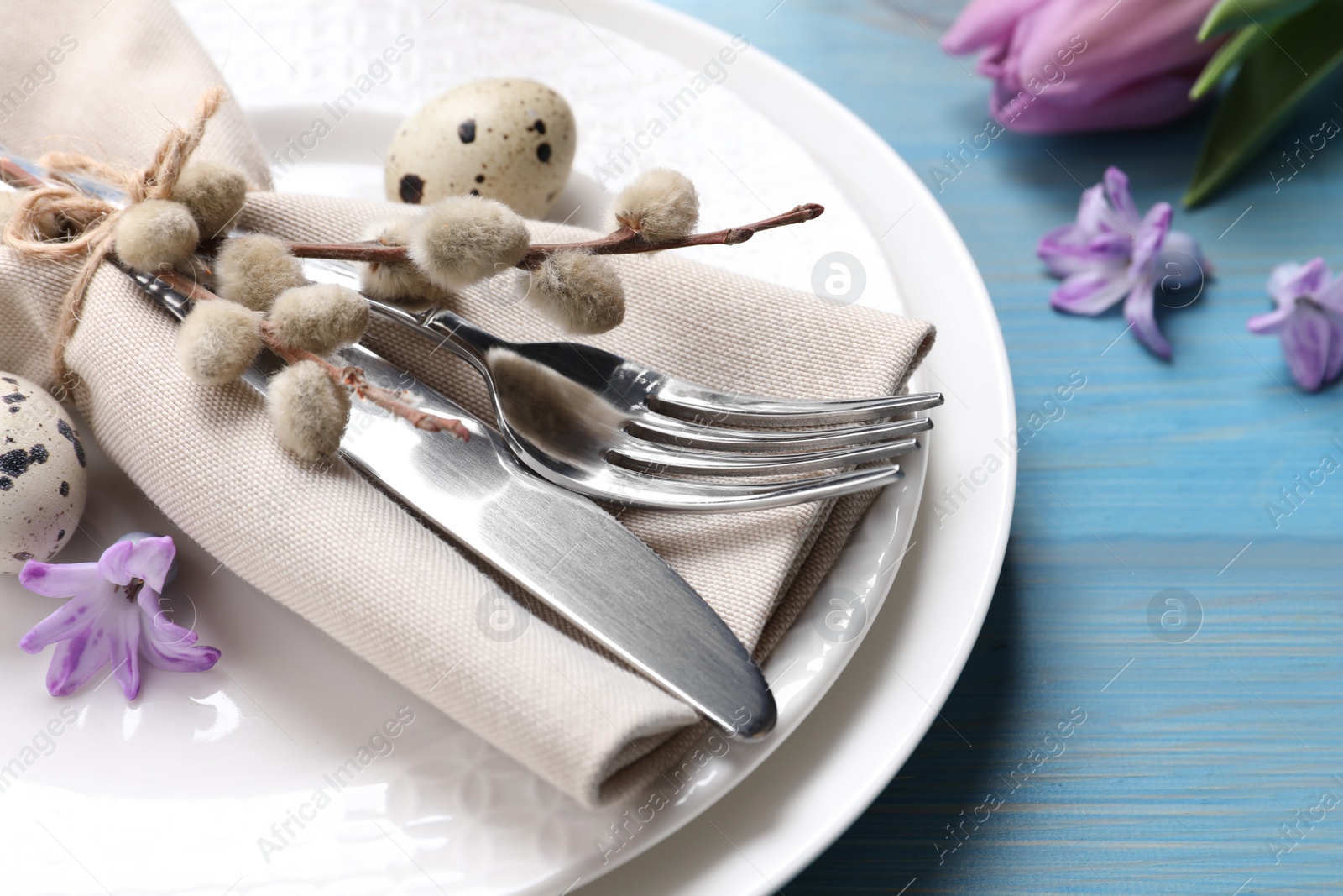 Photo of Festive Easter table setting with eggs and beautiful willow branches on light blue wooden background, closeup