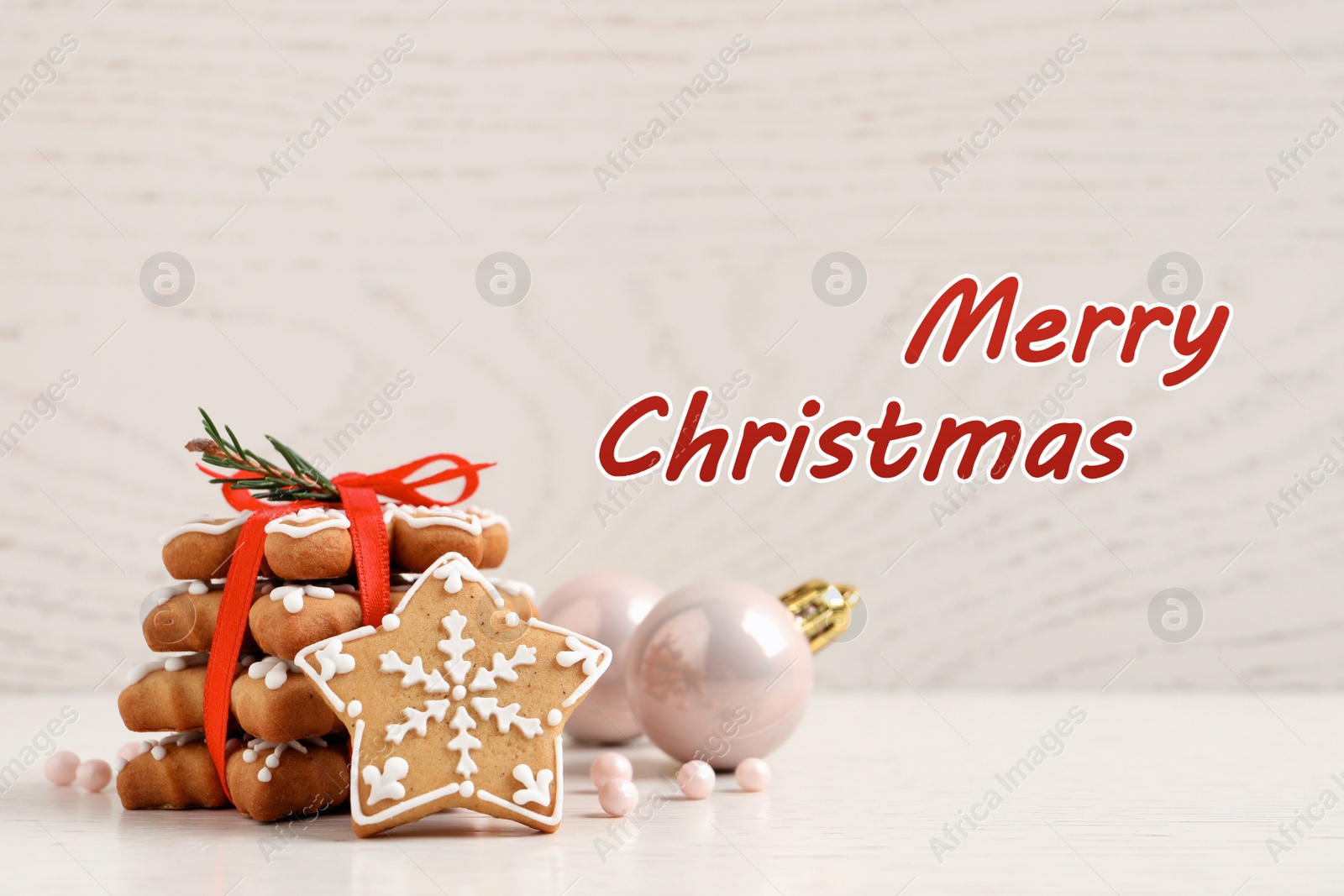 Image of Greeting card with phrase Merry Christmas. Tasty cookies and festive decor on white wooden table