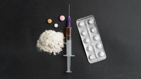 Powder, syringe and pills on black background, flat lay. Hard drugs