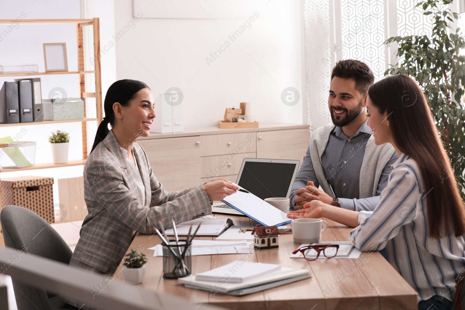 Photo of Happy young couple signing purchase contract in real estate agent's office. Mortgage concept