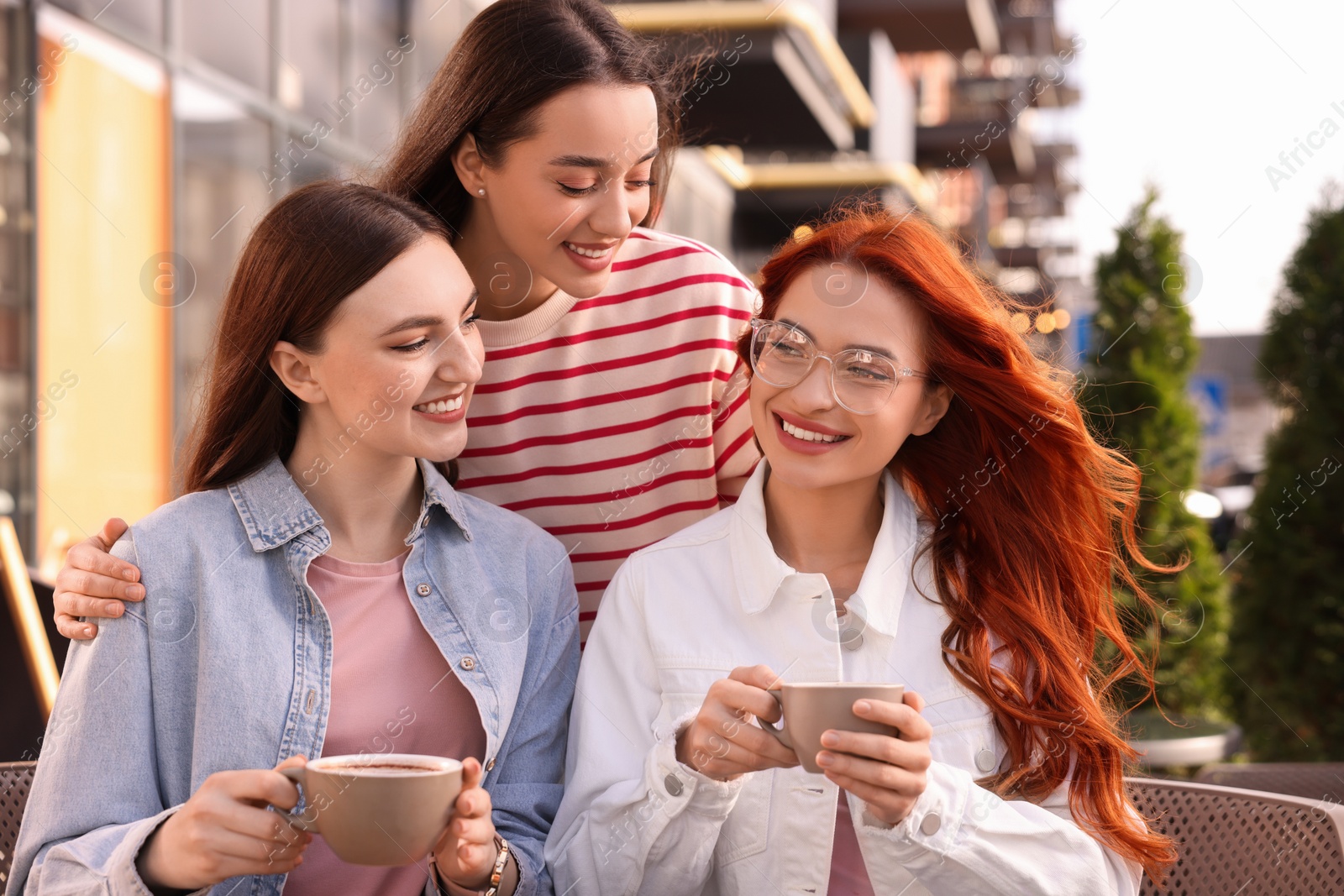 Photo of Happy friends drinking coffee in outdoor cafe