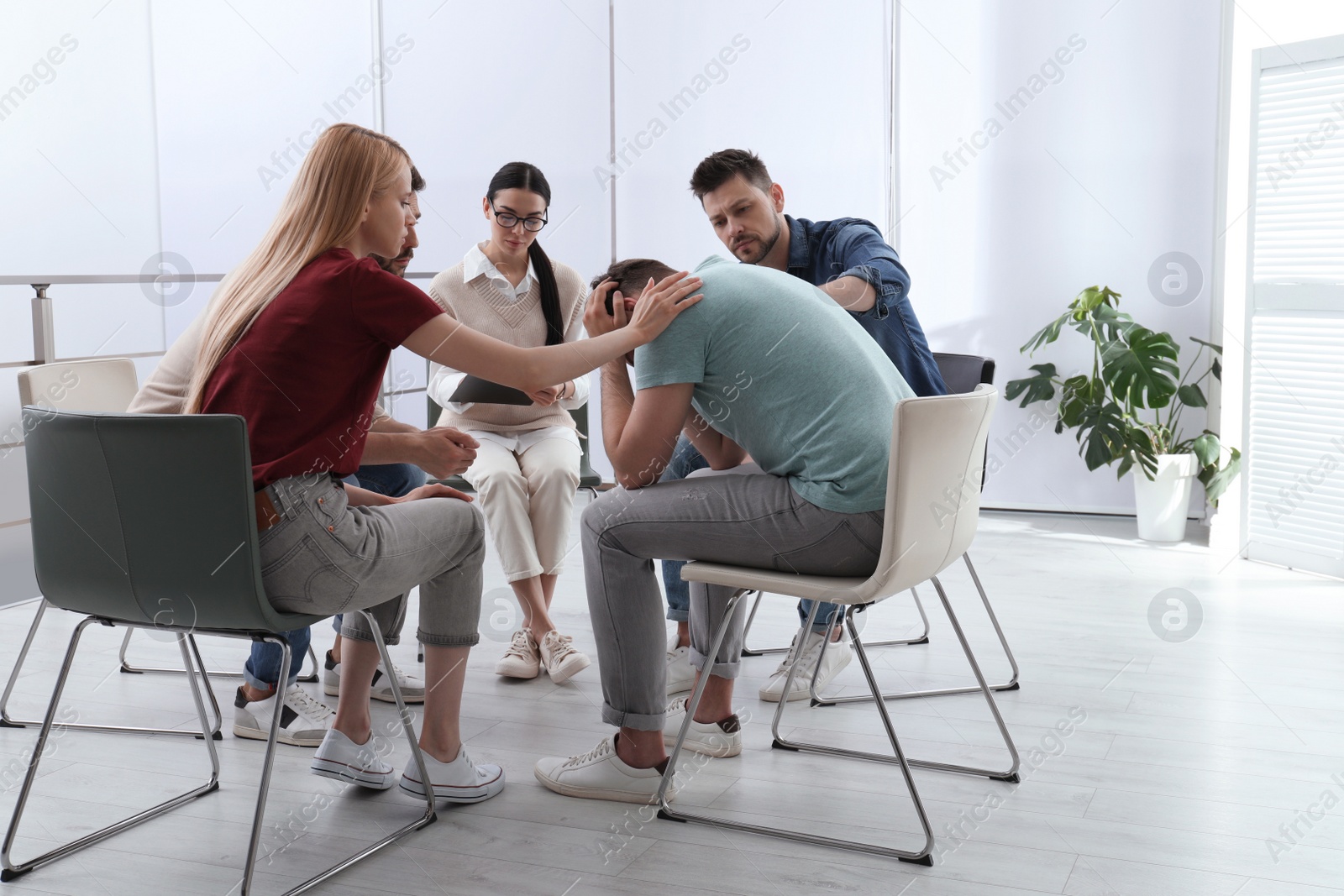 Photo of Psychotherapist working with group of drug addicted people at therapy session indoors