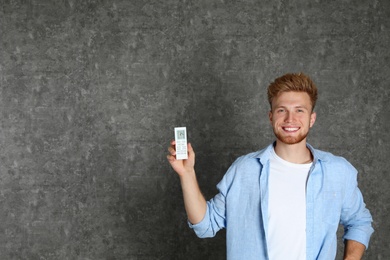 Photo of Young man with air conditioner remote on grey background. Space for text
