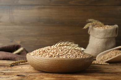 Photo of Bowl with wheat grains on wooden table