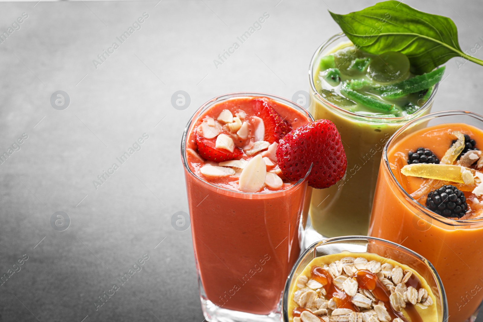 Photo of Many different delicious smoothies on grey table. Space for text