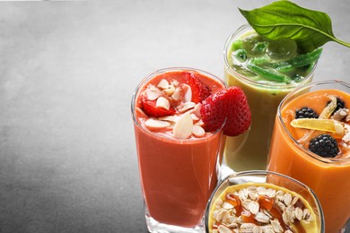 Photo of Many different delicious smoothies on grey table. Space for text