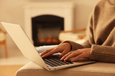 Photo of Woman working on laptop near fireplace at home, closeup