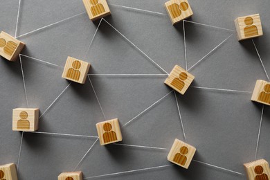 Teamwork. Wooden cubes with human icons linked together symbolizing cooperation on grey background, top view