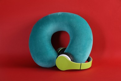 Photo of Turquoise travel pillow and headphones on red background