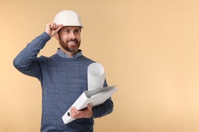 Photo of Architect in hard hat with draft and folder on beige background, space for text