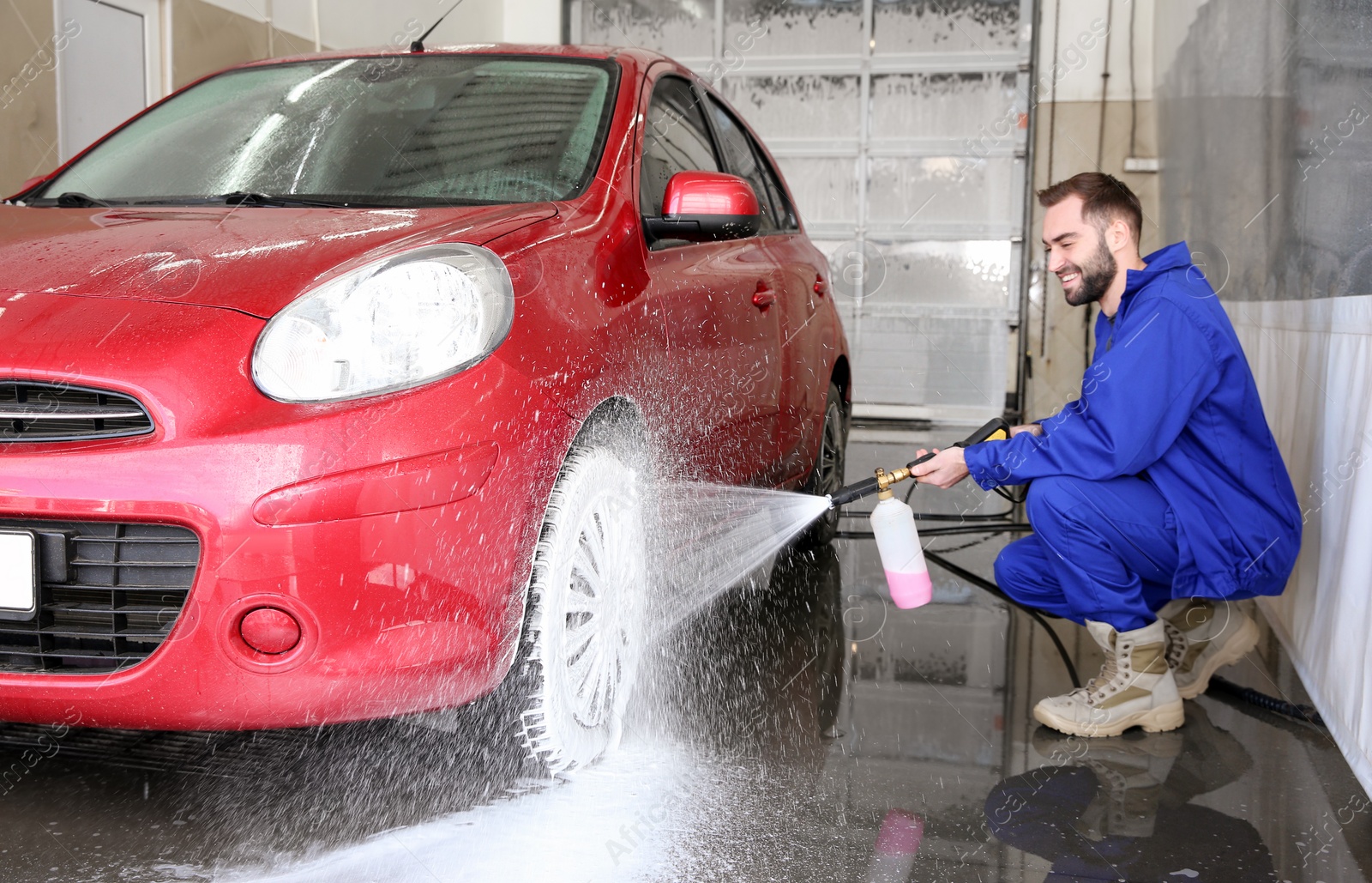 Photo of Worker cleaning automobile with high pressure water jet at car wash