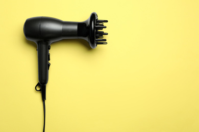 Photo of Hair dryer on yellow background, top view with space for text. Professional hairdresser tool