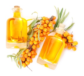 Natural sea buckthorn oil and fresh berries on white background, top view