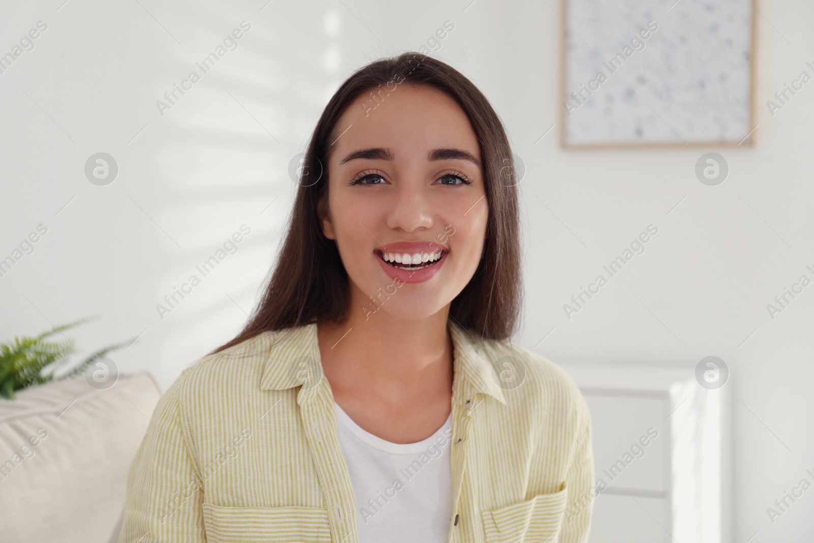 Photo of Young woman talking with her coworkers on video call indoors, view from web camera