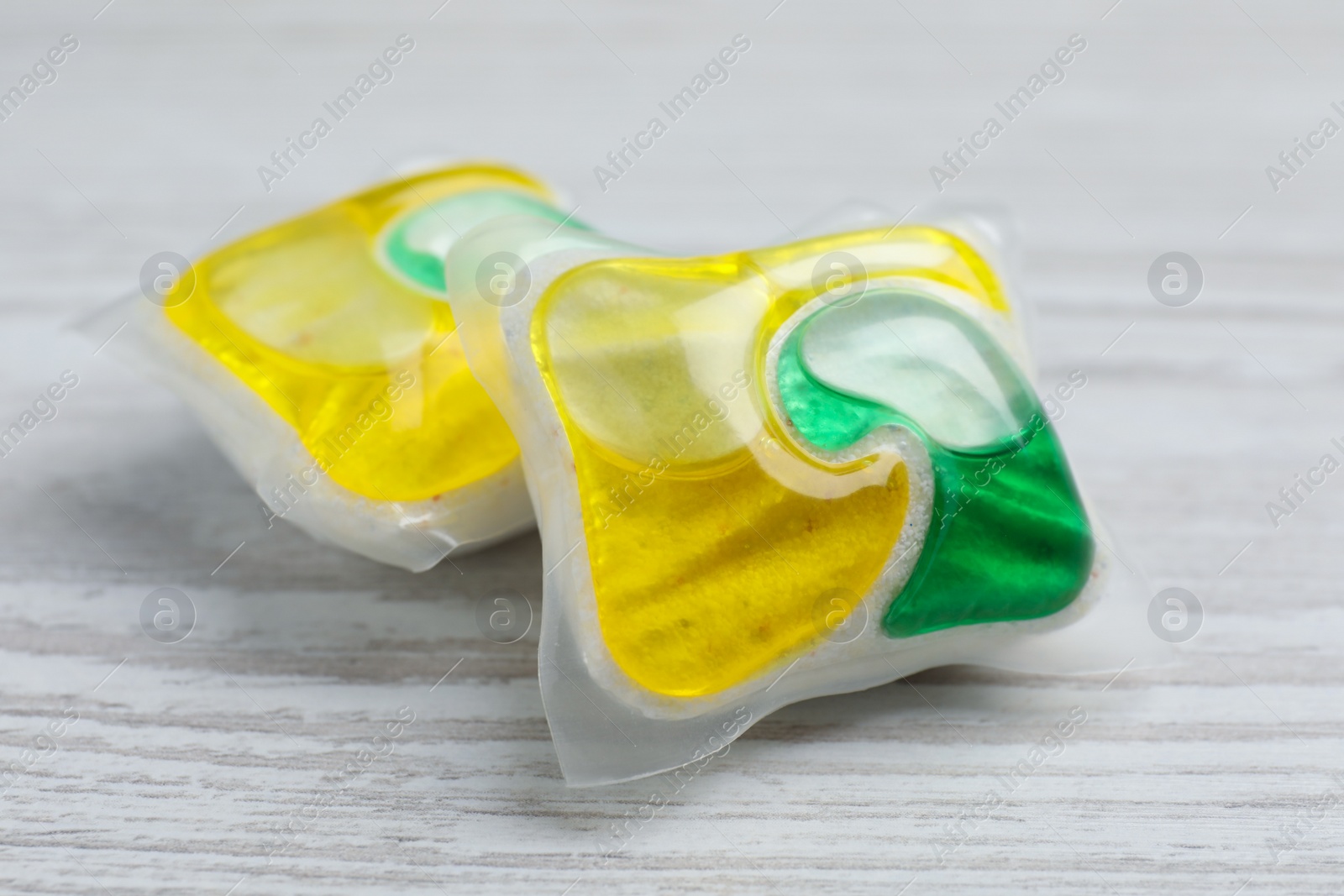 Photo of Dishwasher detergent pods on white wooden table, closeup