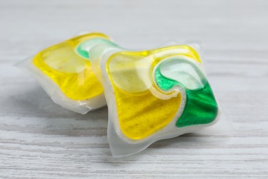 Photo of Dishwasher detergent pods on white wooden table, closeup