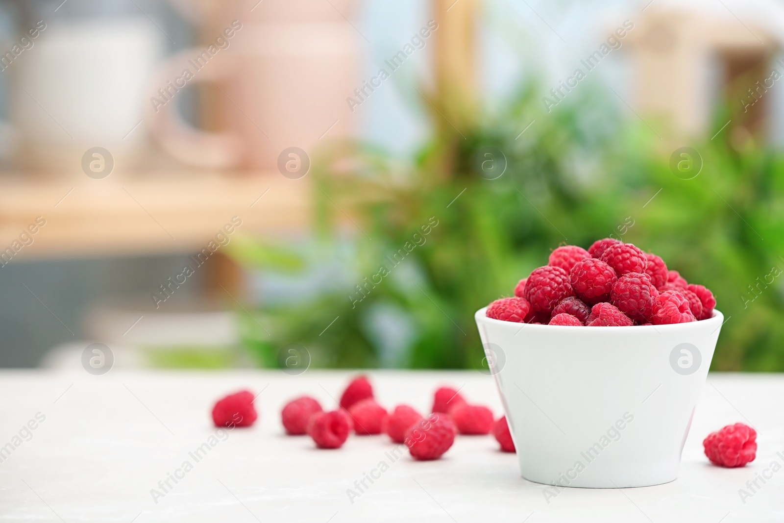 Photo of Bowl with ripe aromatic raspberries on table